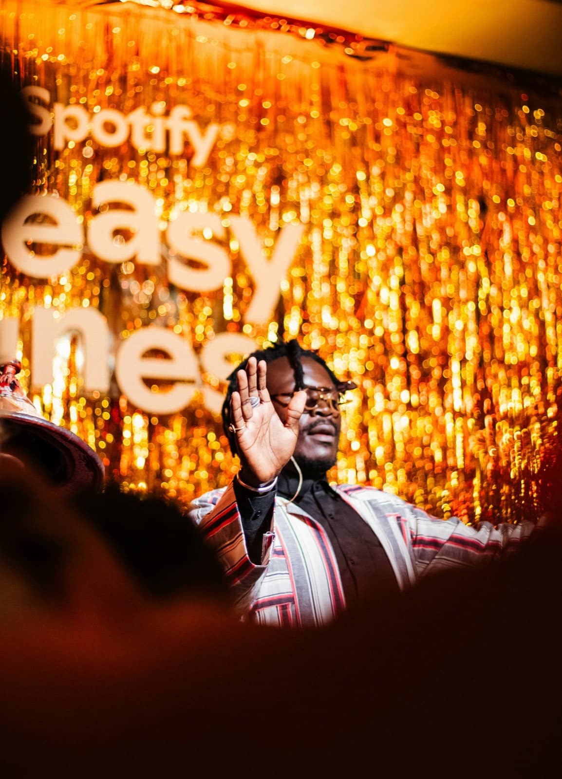 Performer with hands raised on a gold-lit stage